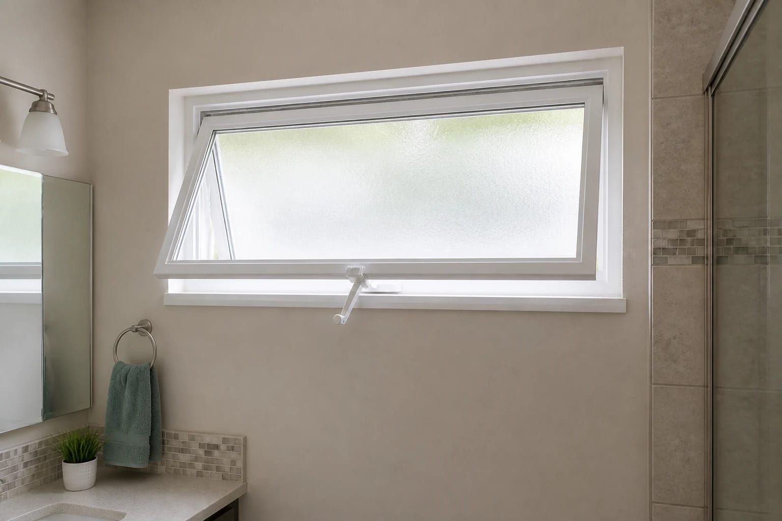 A wide white awning window opened outward from the bottom high on a clean Central Florida bathroom wall