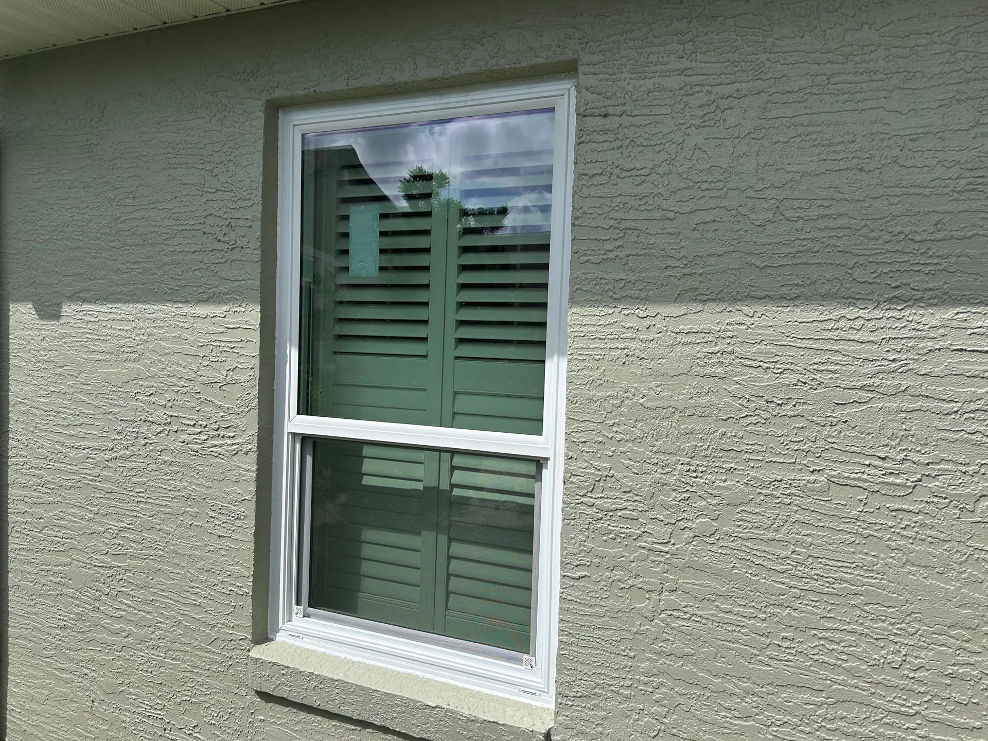 A white single-hung replacement window installed in a light stucco Central Florida home
