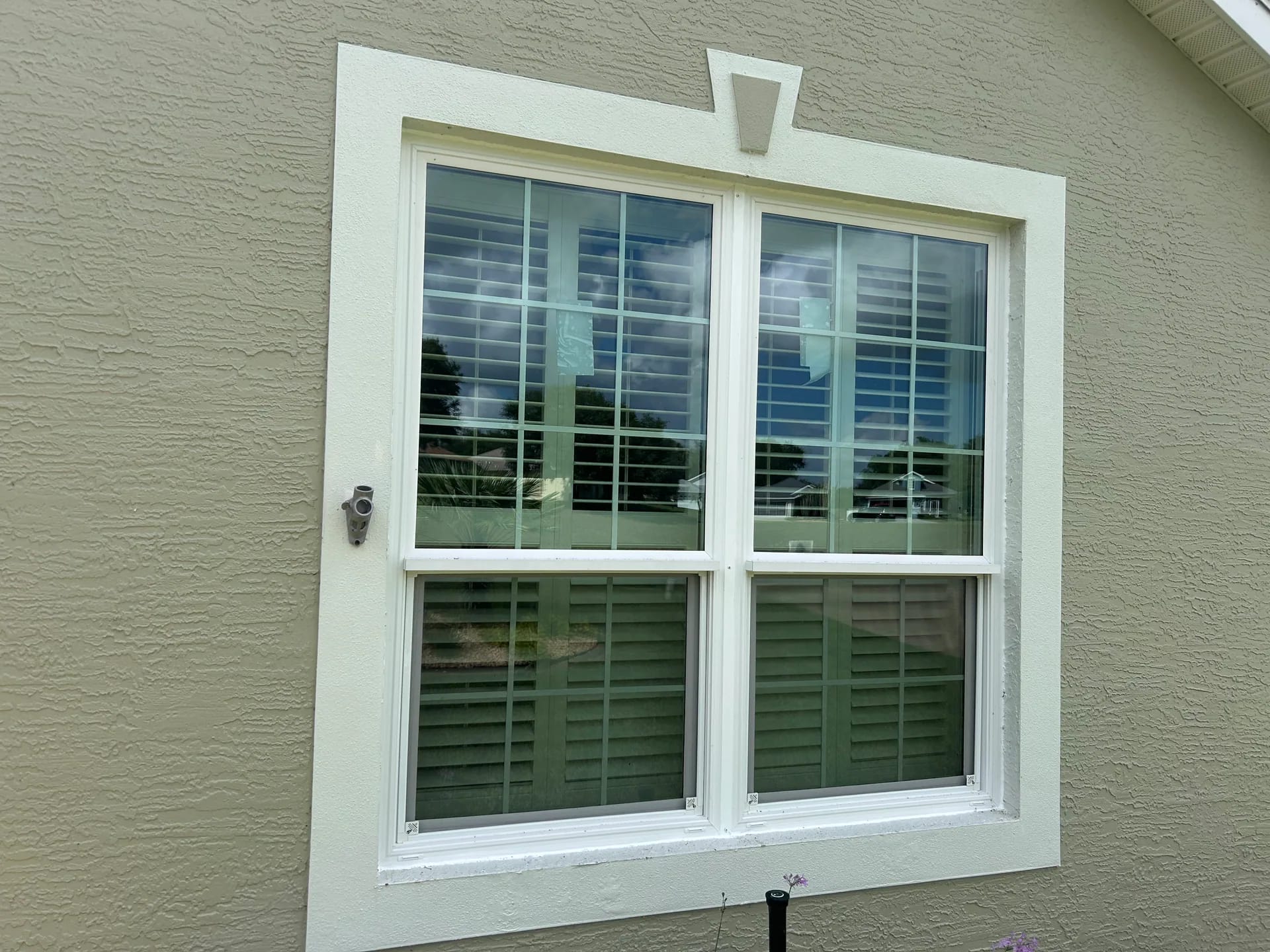 A pair of white replacement windows with colonial grilles installed in a light stucco Central Florida home
