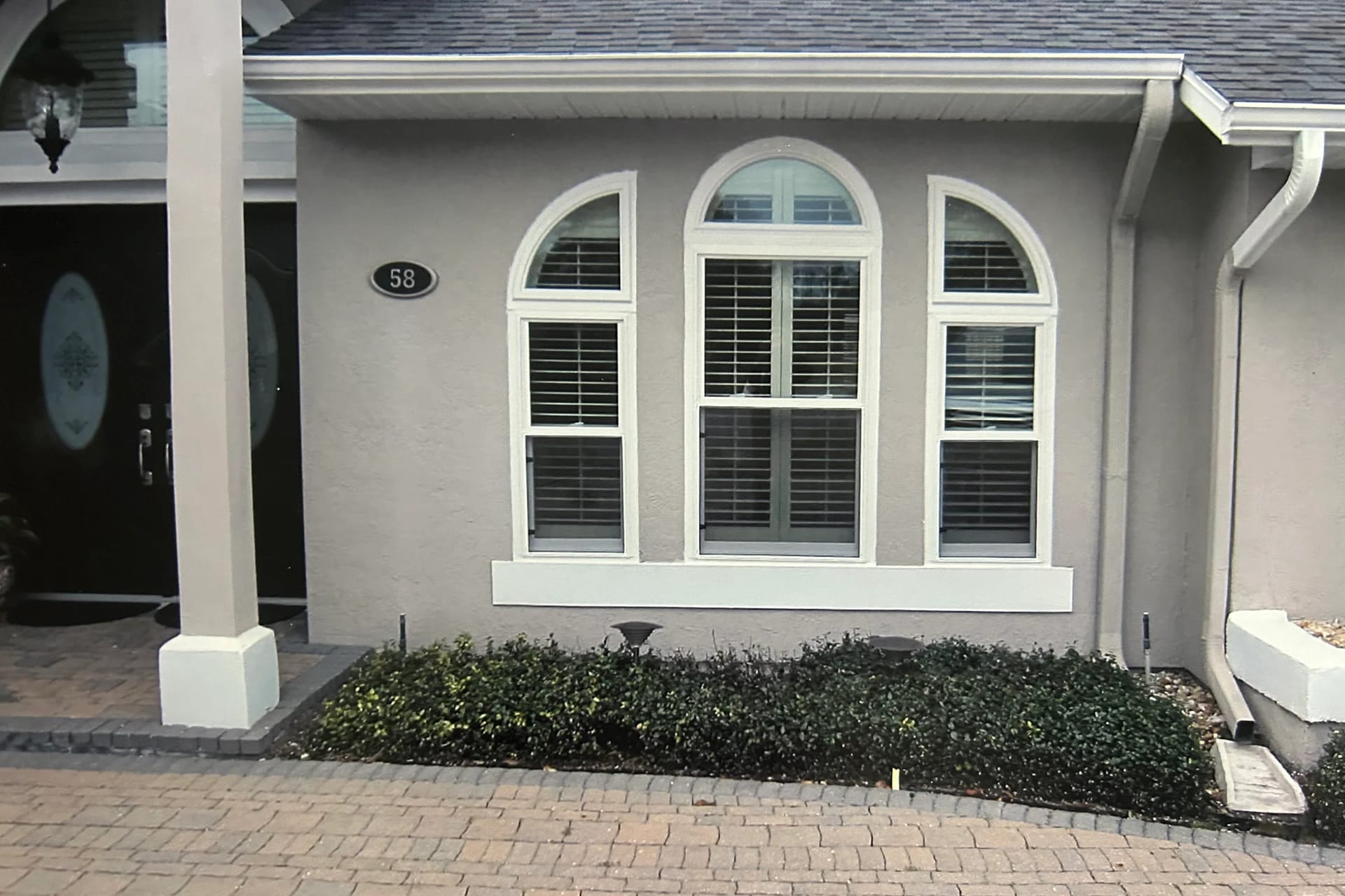 White replacement windows with a central arched transom and curved side transoms on a grey stucco Central Florida home