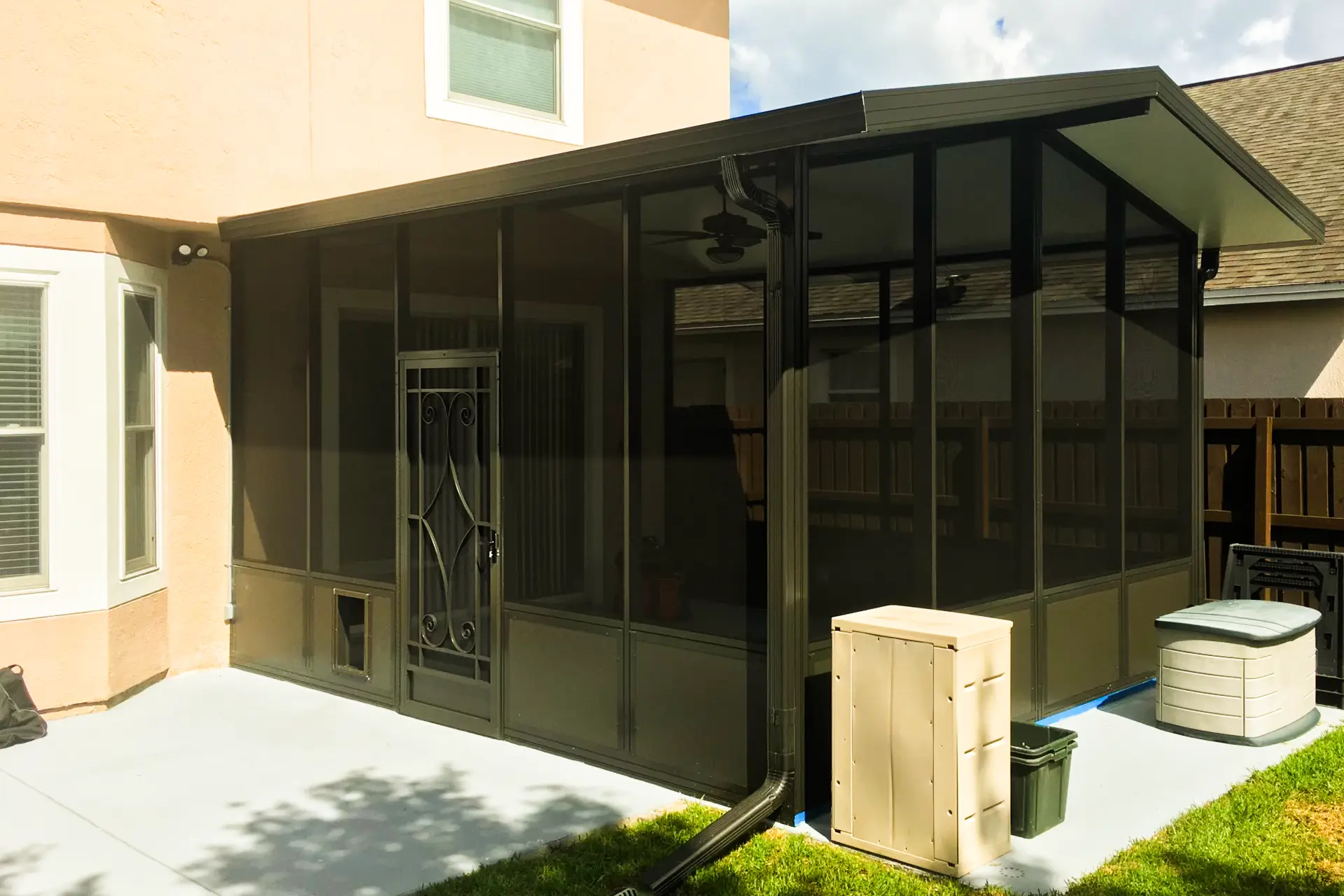 A dark-framed screened patio enclosure across the back of a stucco Florida home