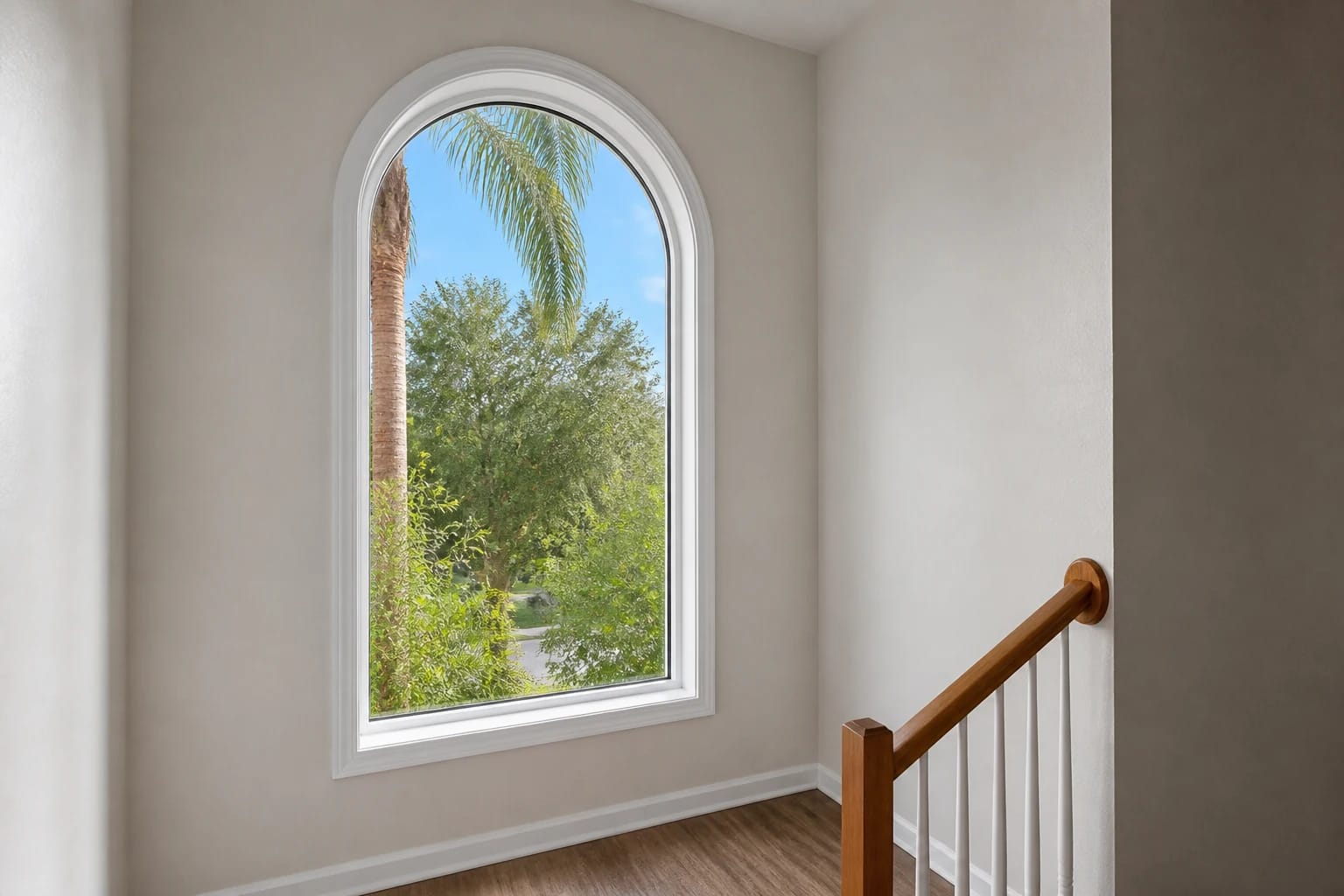 An arched fixed window bringing daylight into a clean Central Florida stair landing